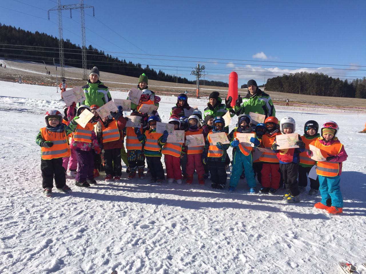 Veľká skupina detí s diplomami a inštruktormi SKI EXPERTS po skončení lyžiarskeho kurzu
